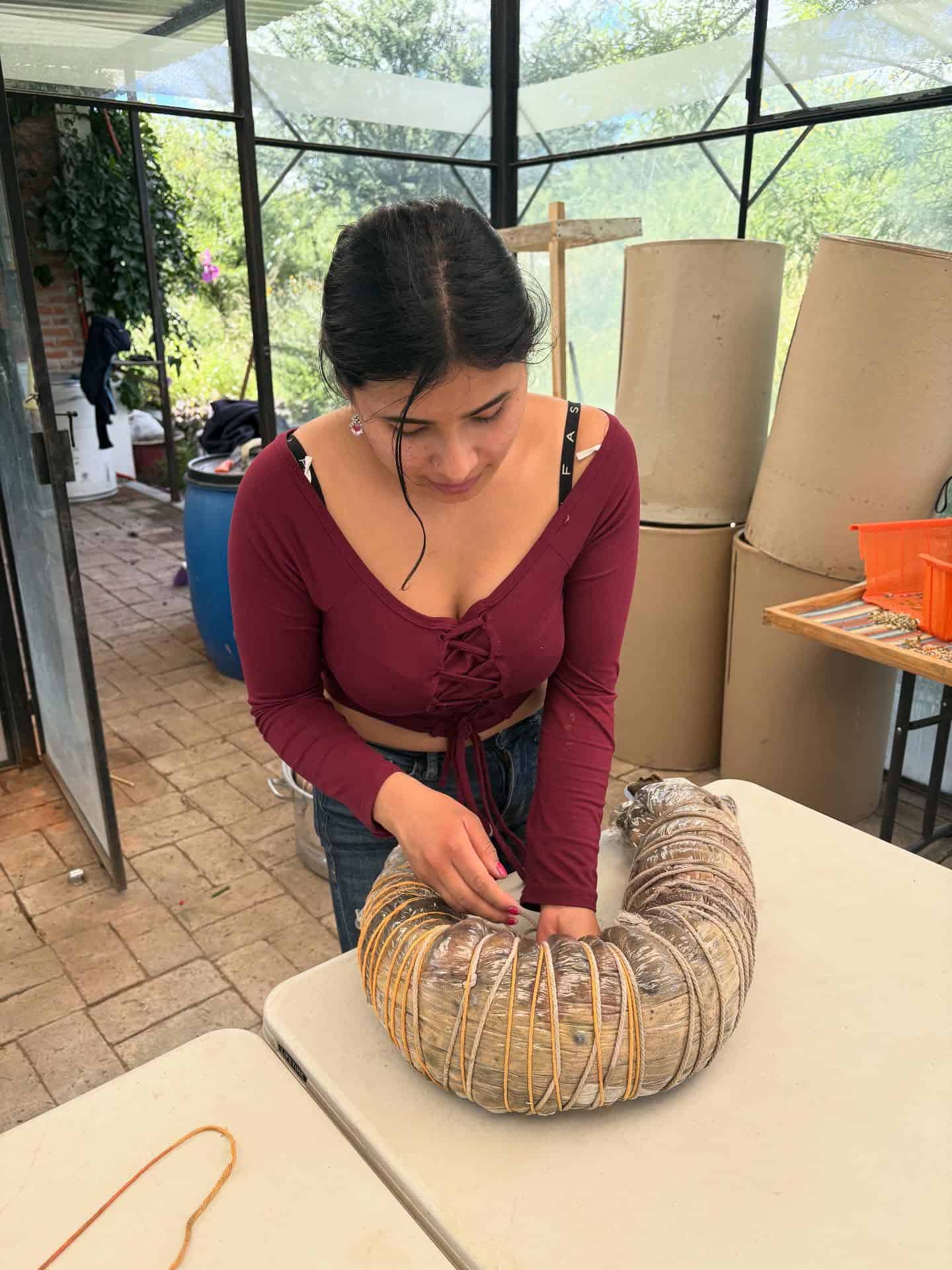 Woman creating a woven art piece with natural materials at SMCF event.